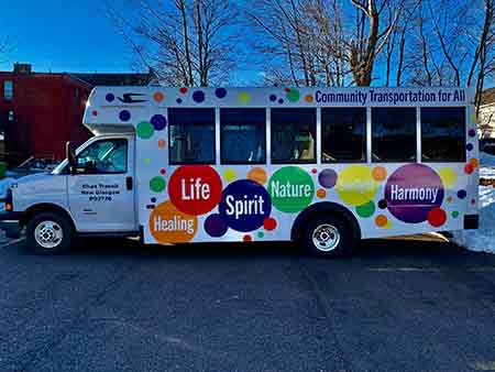 accessible transit bus with colorful dots on outside parked on the street